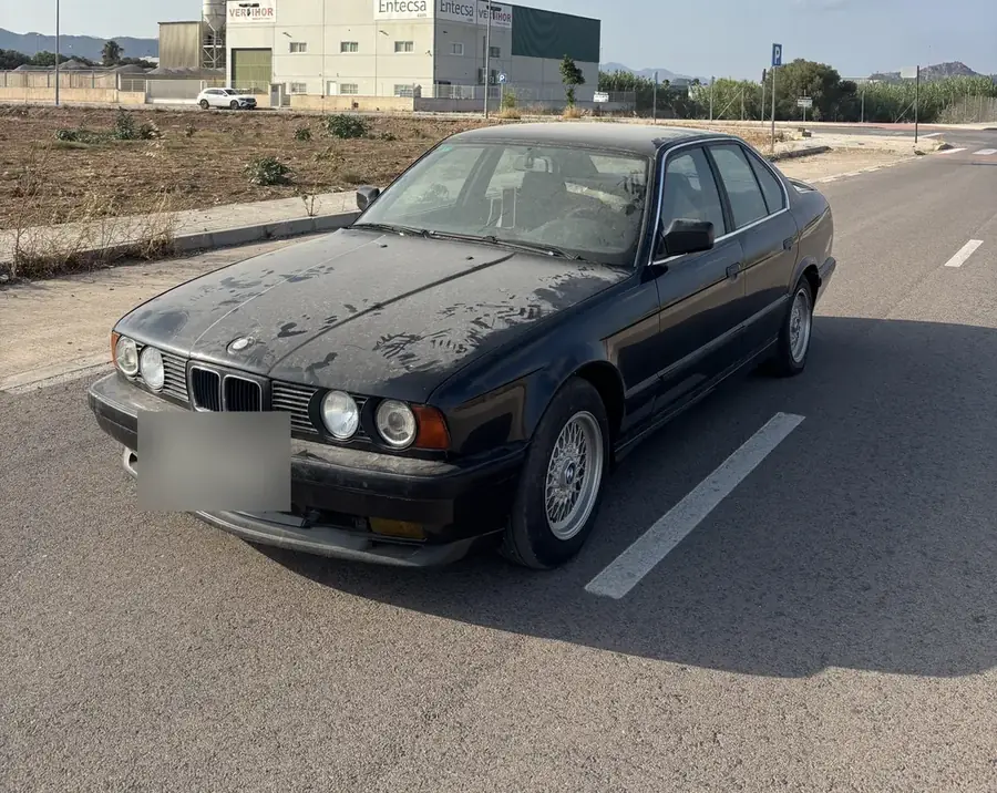 Berlina antigua cubierta de polvo aparcada en la calle
